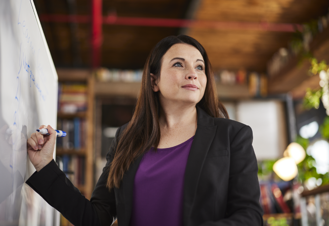 Women standing at dry erase board